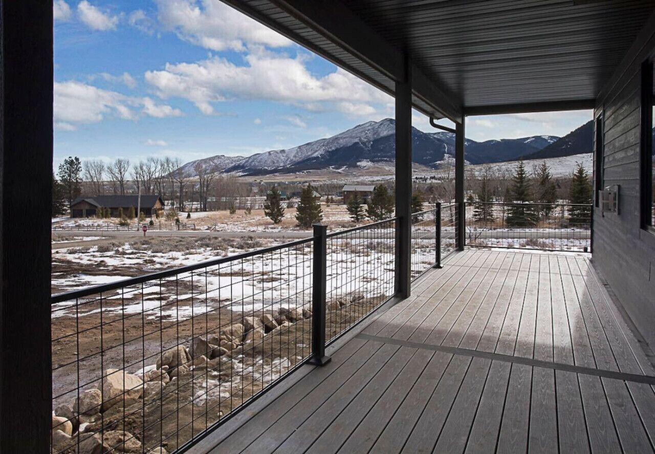 A covered outdoor area with a view of snow-covered mountains and a clear sky.