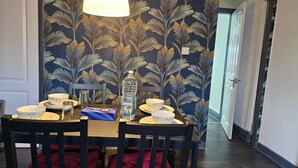 A dining area with a table set for four, chairs, a water bottle, and a box of tissues. - Charming 2-bedroom Home With Modern Amenities (Oldham)