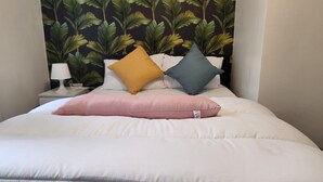A bed with white bedding and three pillows in different colors. - Charming 2-bedroom Home With Modern Amenities (Oldham)