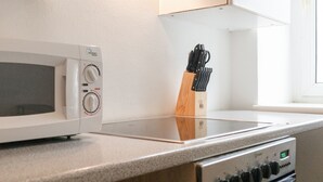 Une cuisine avec un four à micro-ondes blanc, un bloc à couteaux et une cuisinière.