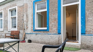 Un bâtiment à l’extérieur en briques, avec un cadre de fenêtre peint en bleu et une porte donnant sur un espace intérieur.