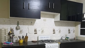 Une cuisine avec des meubles noirs, une cuisinière blanche et un dosseret carrelé.