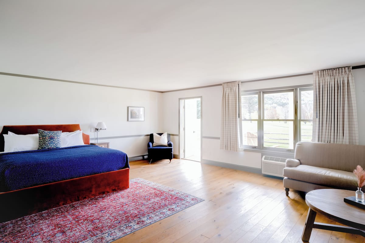 A bedroom with a large bed, a sofa, a small table, and a window with curtains.