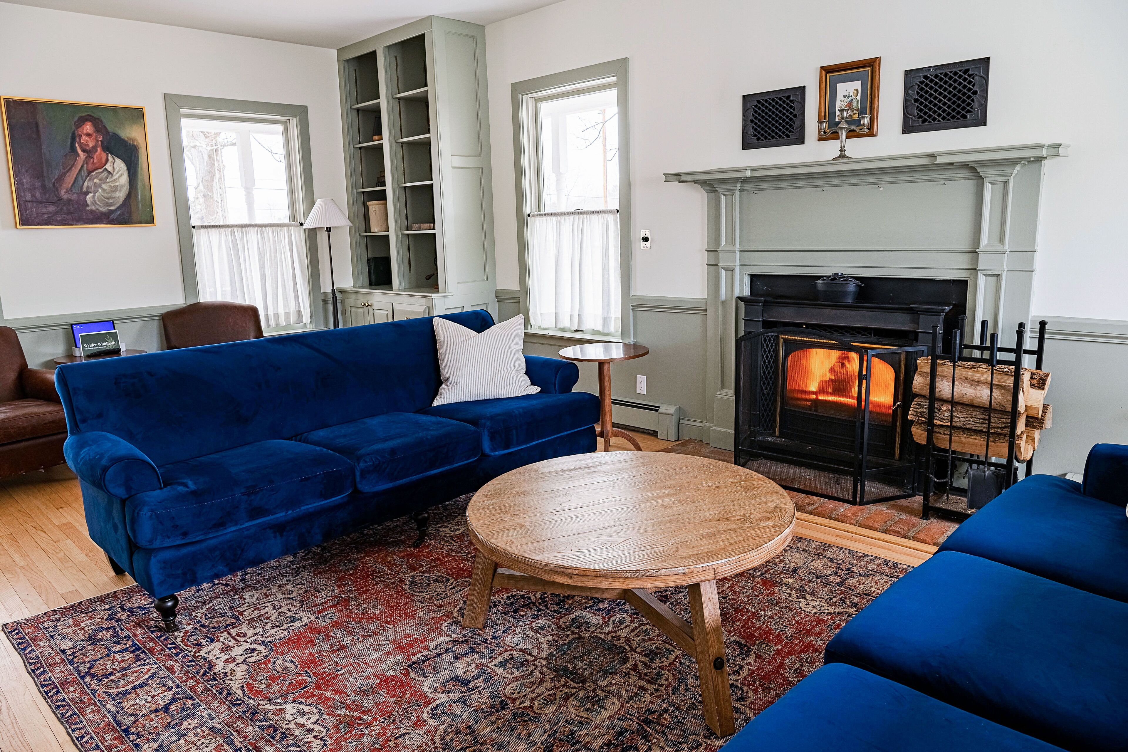 Una sala de estar con un sofá azul, una mesa de centro redonda de madera y una chimenea.