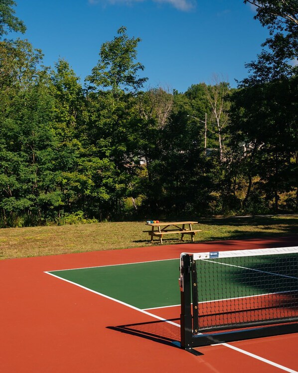 Una cancha de tenis con una mesa de picnic y una red.