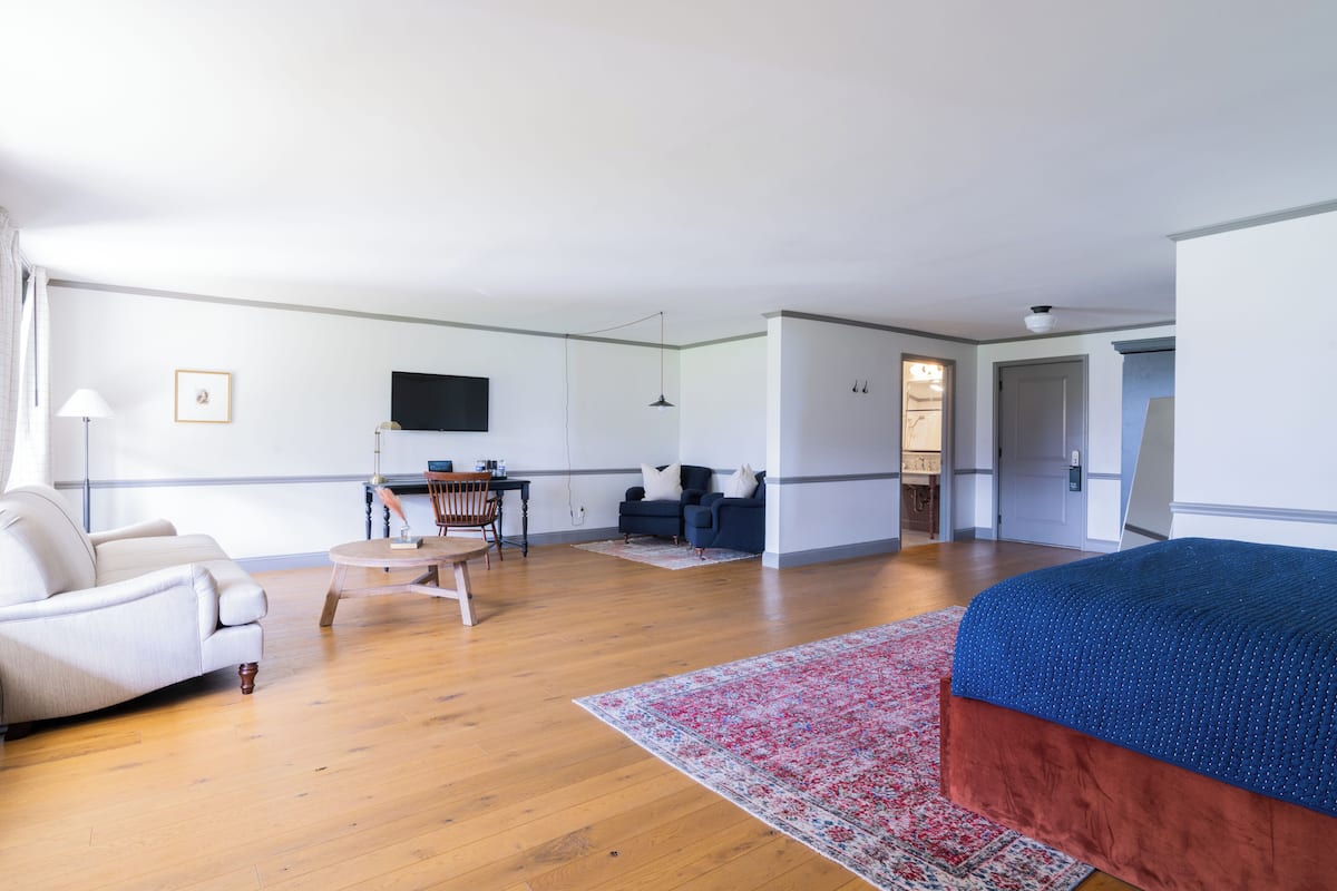 A spacious room with a large bed, a desk, and a seating area.
