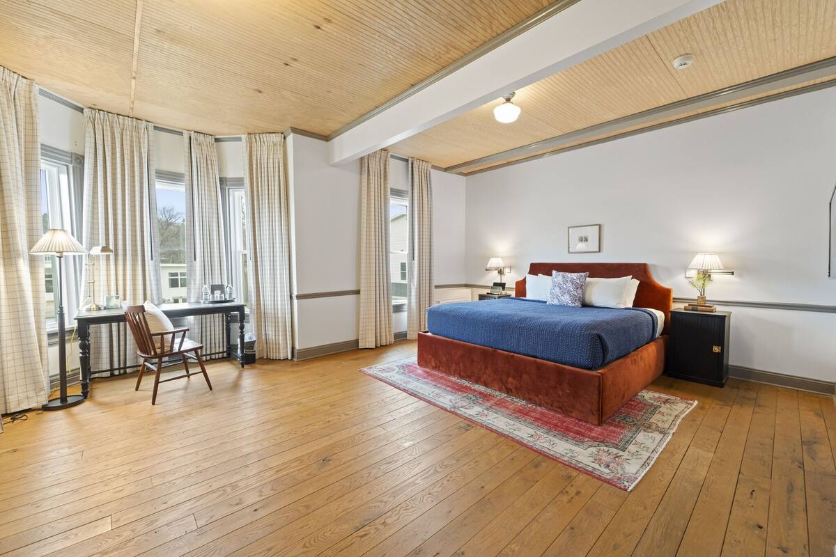 A bedroom with a large bed, a desk, and a chair.