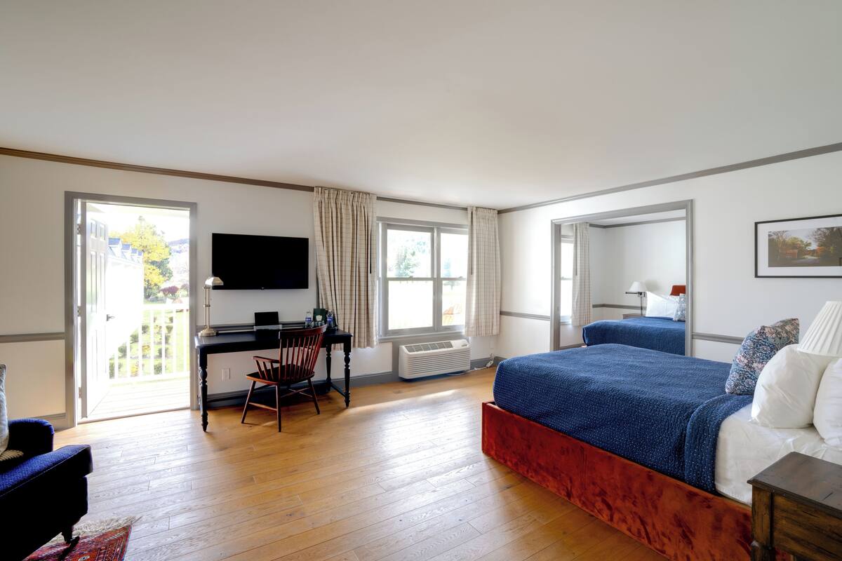 A hotel room with a bed, a desk, a chair, a TV, and a window.
