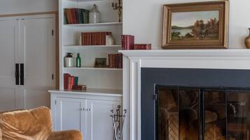 Un accogliente soggiorno con camino, librerie e un lampadario.