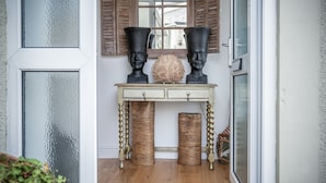 A wooden console table with two black vases and a decorative object in the center, flanked by two wicker baskets. - Town Heights - 3 Bedroom Holiday Home - Tenby (Tenby)