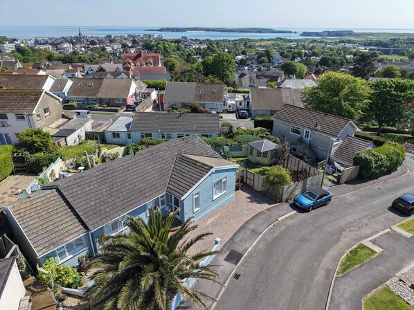 A residential area with houses, a road, and a view of the sea.