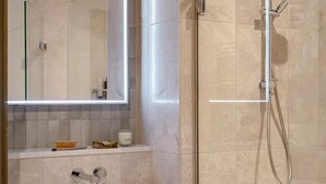 A modern bathroom with a glass-enclosed shower, a white sink, and a mirror with built-in lighting. - Luxurious 2bed Apartment in Greenford Quays (Greenford)