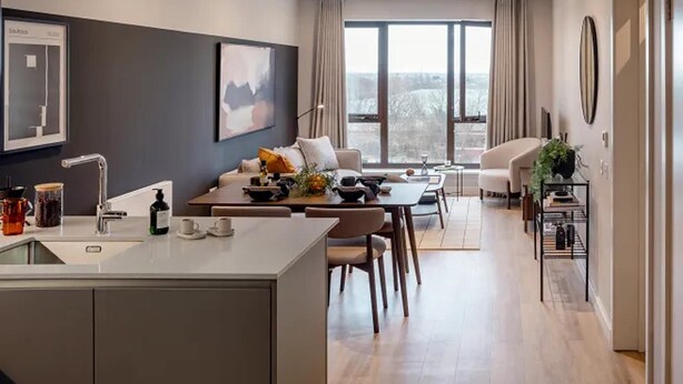A modern kitchen with a central island, dining area with a table and chairs, and a living area with a sofa and a coffee table. - Luxurious 2bed Apartment in Greenford Quays (Greenford)