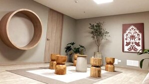 A modern interior with a circular wooden structure, wooden stools, a potted plant, and a decorative wall piece. - NEW LISTING! Mandala: Serenity, Luxury, and Nature! In Envigado. (Cali)