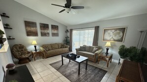 A living room with a sofa, armchairs, a coffee table, and a ceiling fan. - 3/2 Home Minutes To All Theme Parks (Orlando)