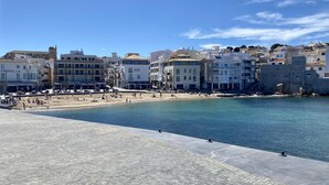 Une ville côtière dotée d’une plage de sable, d’un mur de pierre et d’immeubles avec des balcons.