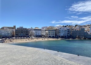 En kystby med en sandstrand, en murstensmur og bygninger med altaner.