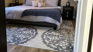 A bedroom with a bed, two nightstands, a ceiling fan, a wall-mounted painting, and a patterned rug. - Cozy and Comfortable home with easy access to Hwy 60 and Springfield! (Republic)