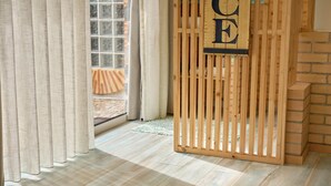 A room with a wooden partition, a window with curtains, and a brick wall. - Casas Maravilha - Piscina by Homie (Calheta)