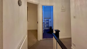 A hallway with a ceiling fan, a door leading to a room with a blue door, and a small hanging light fixture. - Comfy and Spacious 5-bed House in Cambridge (Cambridge)