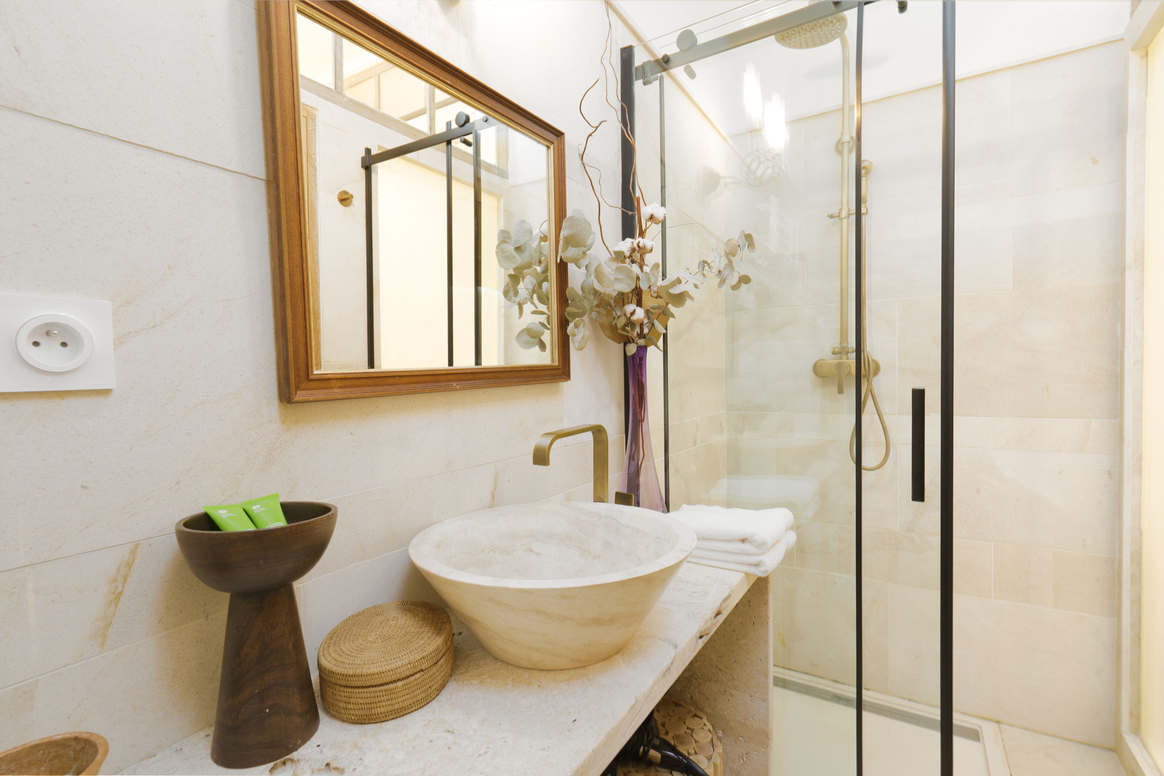 Une salle de bain avec un grand miroir, un lavabo sur colonne, une douche et un porte-serviettes.