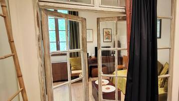 Una habitación con un ventanal grande, una escalera y una cortina negra.