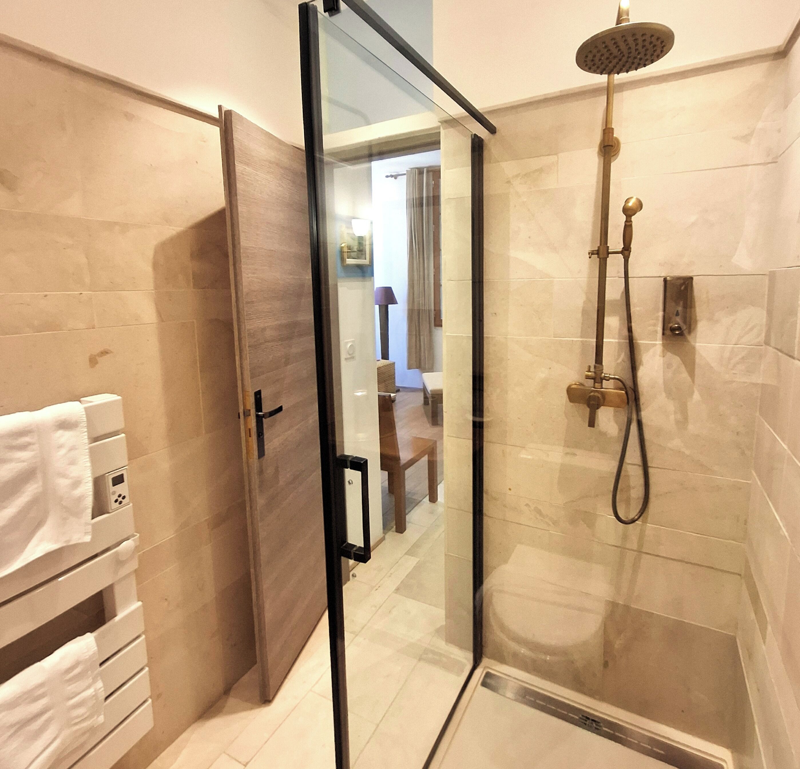 Ein modernes Badezimmer mit Duschkabine aus Glas, einem Handtuchhalter und einer Bedienkonsole.