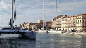 Un puerto deportivo con veleros amarrados, rodeado de edificios históricos con balcones y ventanas de arco.