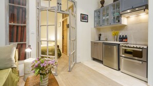 Cocina compacta con horno integrado, un refrigerador pequeño y una zona de comedor con mesa y silla.
