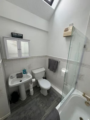 A bathroom with a toilet, sink, and shower.