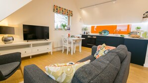 A modern apartment with a living room, dining area, and kitchen. - Ty Haul - sleeps 2 guests  in 1 bedroom (Llanfaelog)