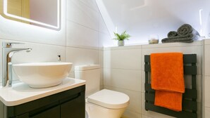 A modern bathroom with a white sink, toilet, and towel rack. - Ty Haul - sleeps 2 guests  in 1 bedroom (Llanfaelog)