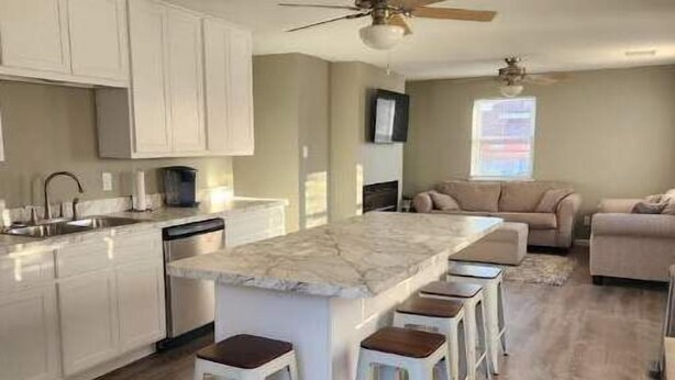 A modern kitchen with a marble island, white bar stools, and a ceiling fan. - Rafton 2 Home (Grafton)