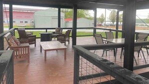 An outdoor patio area with wooden flooring, metal railings, and various seating arrangements including chairs and a bench. - Rafton 2 Home (Grafton)