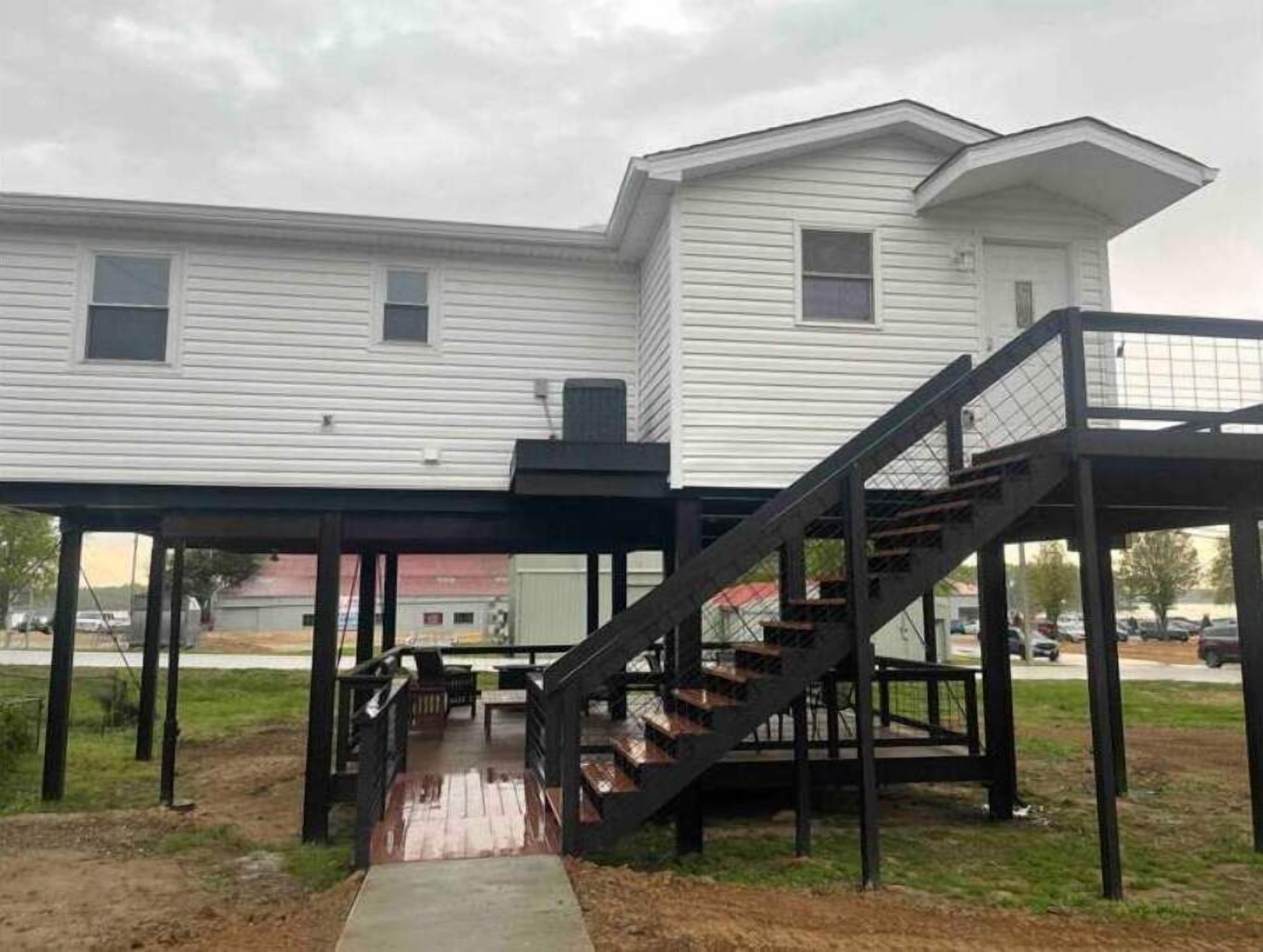 Una casa de dos pisos con un porche cubierto y una escalera que lleva a un nivel superior.