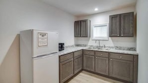 A compact kitchen with a refrigerator, a sink, and wooden cabinets. - Rafton Inn Vacation Cottage 19 (Grafton)