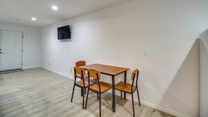 A room with a wooden dining table and four chairs, white walls, and a door. - Rafton Inn Vacation Cottage 19 (Grafton)