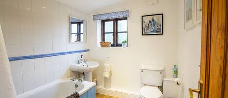 A bathroom with a bathtub, sink, toilet, and a window with a view of a cityscape.