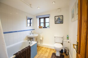Ein Badezimmer mit Badewanne, Waschbecken, Toilette und einem Fenster mit Blick auf die Stadt.