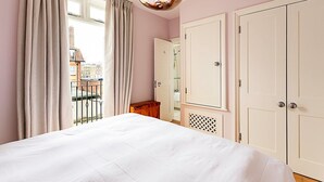 Un dormitorio con cama, armario, espejo y ventana con cortinas.