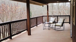 A covered wooden deck with two rocking chairs and a small table.