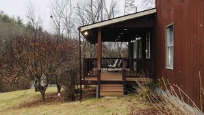 A wooden cabin with a porch, a chair, and a small table.