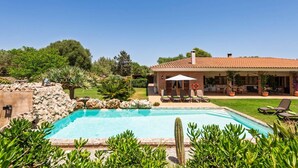 A pool area with a house in the background, surrounded by greenery and a clear sky. - Villa Son Tretze by Villa Plus (Biniparrell)