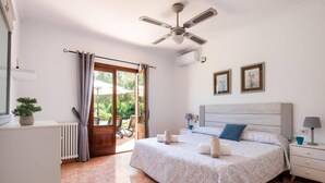 A bedroom with a bed, a ceiling fan, a radiator, a potted plant, and a view of the outdoors. - Villa Son Tretze by Villa Plus (Biniparrell)