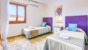 A bedroom with two beds, a window, an air conditioner, a nightstand, and a painting. - Villa Casa Galan by Villa Plus (Mallorca)