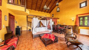 Ein Zimmer mit einem Himmelbett, einem Essbereich mit Holzkästen und einer Treppe, die in ein Obergeschoss führt.