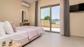Une chambre d’hôtel comprenant un lit, une table de chevet agrémentée de deux plantes en pot, un téléviseur à écran plat fixé au mur et une porte-fenêtre coulissante donnant sur un balcon extérieur.