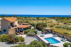 Una villa moderna con piscina, mobiliario exterior y vistas al mar.