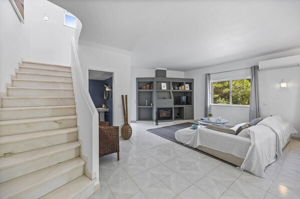 A modern living room with a fireplace, a sofa set, and a dining area with a table and chairs.