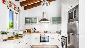A modern kitchen with white cabinets, a stainless steel oven, a built-in microwave, and a washing machine. - Villa Anchorage by Villa Plus (Puerto Luz)